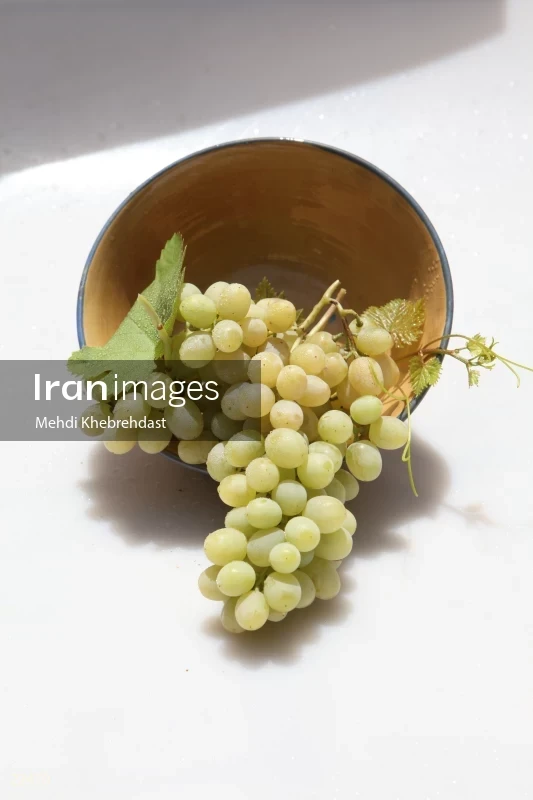 Bunch of green grapes in bowl on white background