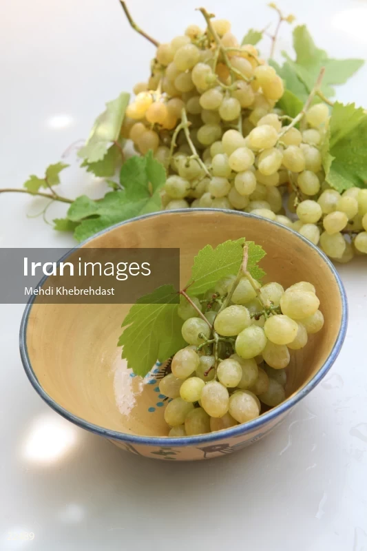 Bunch of green grapes in bowl on white background